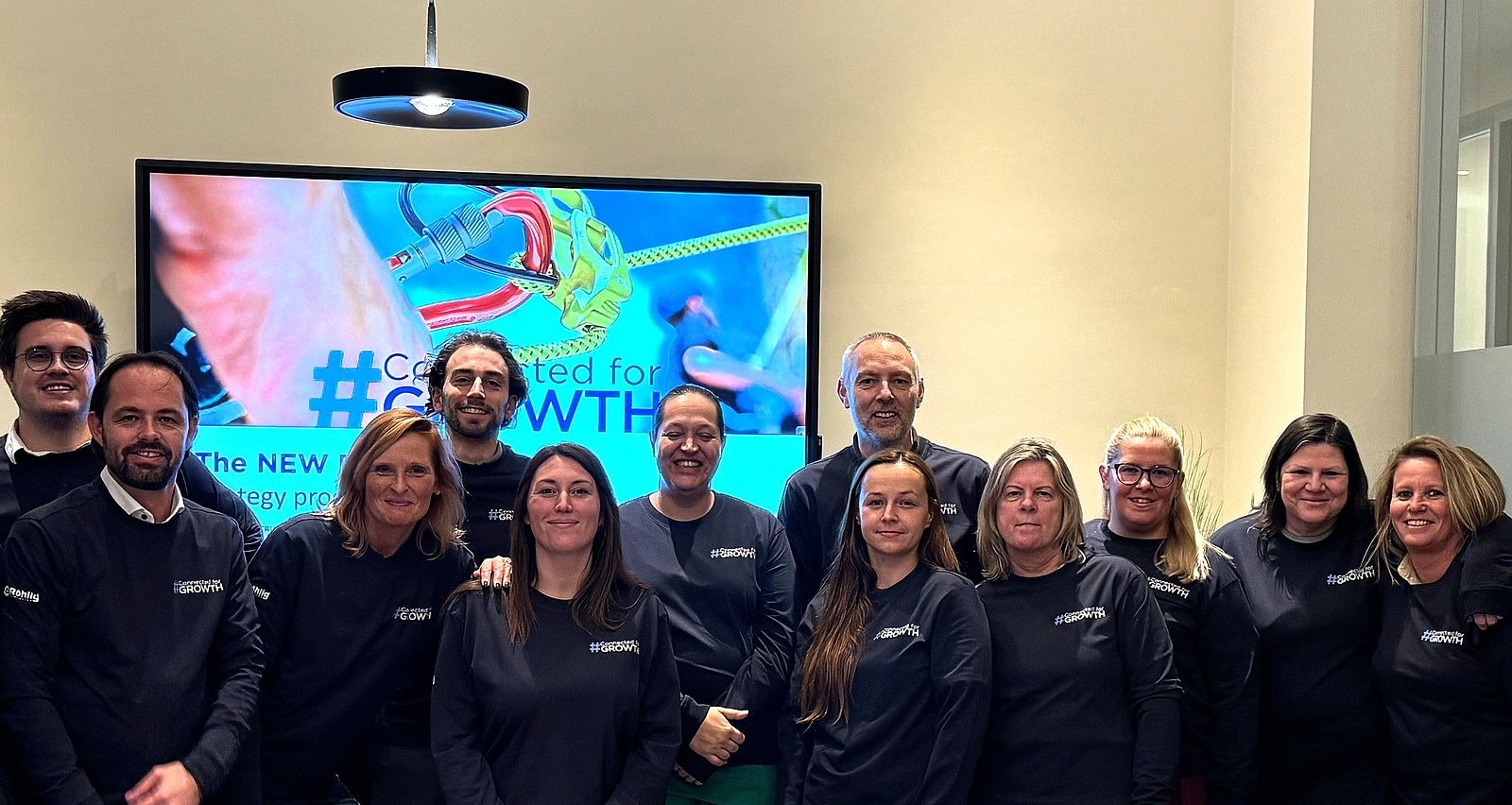 Gruppe von Menschen in ähnlichen Sweatshirts, die in die Kamera lächeln