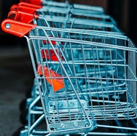 A line of silver shopping carts with red handles and a red toddler seats.